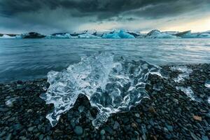 Ice cracked on black beach and iceberg floating in Jokulsarlon glacier lagoon photo