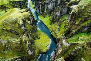 Rugged moss Fjadrargljufur canyon with Fjadra river flowing through in summer at Iceland photo