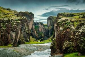 Rugged moss Fjadrargljufur canyon with Fjadra river flowing through in summer at Iceland photo