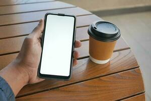 using smart phone with white screen and paper cup on table photo