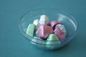 chocolate candy in different colors in a bowl on table photo