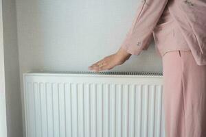 mujer calentamiento manos cerca eléctrico calentador a hogar. foto