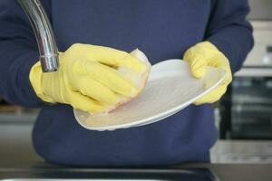 hand with gloves cleaning a plate with sponge photo