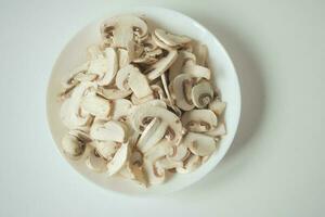 Fresh champignons mushroom in a white bowl on table photo