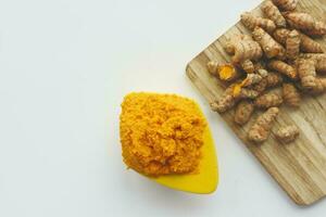 turmeric root and paste in a bowl on white background photo