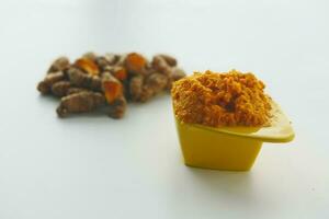 turmeric root and paste in a bowl on white background photo