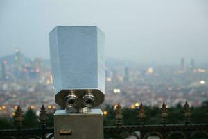 Coin-operated binoculars looking out over city , photo
