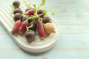 Fresh red radish bundle on chopping board on table photo