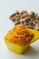 turmeric root and paste in a bowl on white background photo