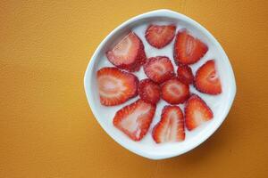 Ripe Red Strawberries and yogurt n a bowl on table photo