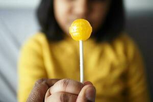 child holding yellow color lollipop candy photo