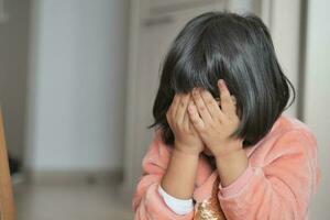 a upset child girl cover her face with hand photo