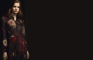 Young girl in a dress with a color print on a black background. photo