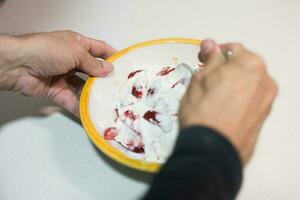 manos de adulto hombre mezcla yogur y rebanado fresas foto