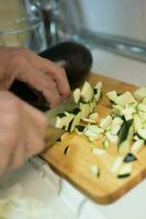 Human hands cutting zucchini into pieces photo