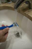 Hand of caucasian man washing a razor with water photo