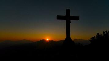 Top of a mountain with a cross in the setting sun photo