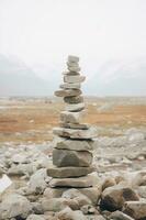 un minimalista inukshuk hecho de apilado piedras señalando el camino a través de el Alaska tundra. ai generativo foto