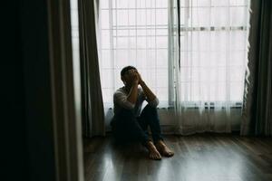 solo hombre silueta curioso a el ventana cerrado con cortinas en dormitorio. hombre soportes a ventana solo foto