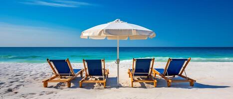 Summer chairs and umbrellas are set up on a tropical beach with a backdrop of blue sky and sea. photo