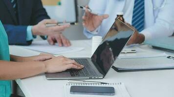 Group of healthcare workers and businessman using laptop while having a meeting in the office. Focus is on young doctor. video