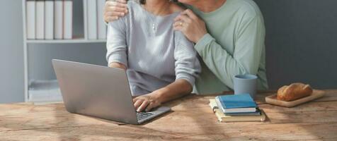 Embraced mature couple surfing the Internet on laptop at home photo