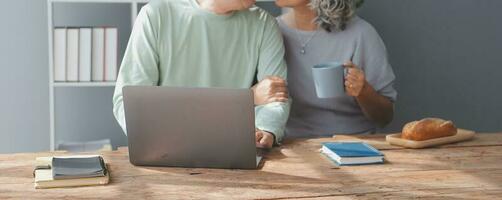 Embraced mature couple surfing the Internet on laptop at home photo