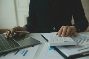 Close up businessman hand using calculator and working with laptop calculate about finance accounting at coffeeshop outdor.finance accounting concept photo