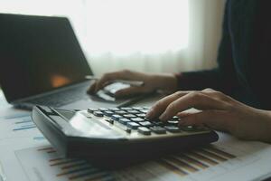 Close up businessman hand using calculator and working with laptop calculate about finance accounting at coffeeshop outdor.finance accounting concept photo