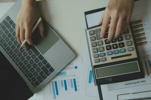 cierre la mano del hombre de negocios usando una calculadora y trabajando con una computadora portátil para calcular la contabilidad financiera en la cafetería outdor.concepto de contabilidad financiera foto