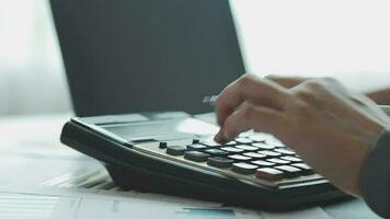 primo piano la mano dell'uomo d'affari utilizzando la calcolatrice e lavorando con il laptop calcolare la contabilità finanziaria al coffeeshop outdor.concetto di contabilità finanziaria video