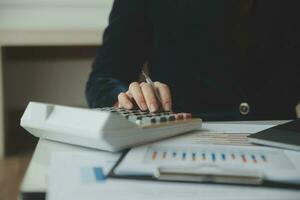 Close up businessman hand using calculator and working with laptop calculate about finance accounting at coffeeshop outdor.finance accounting concept photo