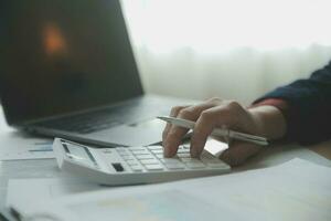 Close up businessman hand using calculator and working with laptop calculate about finance accounting at coffeeshop outdor.finance accounting concept photo
