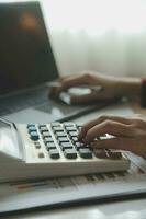 Close up businessman hand using calculator and working with laptop calculate about finance accounting at coffeeshop outdor.finance accounting concept photo