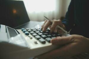 Close up businessman hand using calculator and working with laptop calculate about finance accounting at coffeeshop outdor.finance accounting concept photo