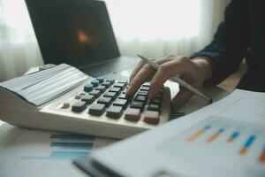 Close up businessman hand using calculator and working with laptop calculate about finance accounting at coffeeshop outdor.finance accounting concept photo