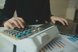 Close up businessman hand using calculator and working with laptop calculate about finance accounting at coffeeshop outdor.finance accounting concept photo