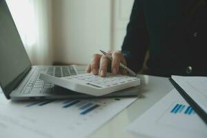Close up businessman hand using calculator and working with laptop calculate about finance accounting at coffeeshop outdor.finance accounting concept photo