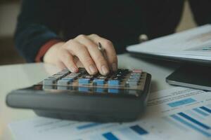 Close up businessman hand using calculator and working with laptop calculate about finance accounting at coffeeshop outdor.finance accounting concept photo