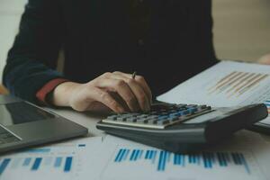 Close up businessman hand using calculator and working with laptop calculate about finance accounting at coffeeshop outdor.finance accounting concept photo