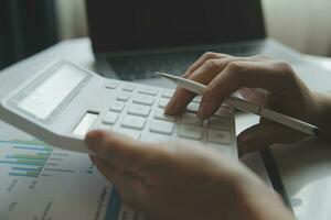 Close up businessman hand using calculator and working with laptop calculate about finance accounting at coffeeshop outdor.finance accounting concept photo