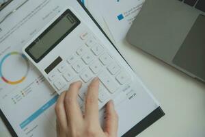 Close up businessman hand using calculator and working with laptop calculate about finance accounting at coffeeshop outdor.finance accounting concept photo