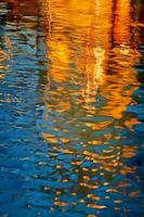 An orange and blue reflection in the water, in the style of light gold and indigo. AI generative photo