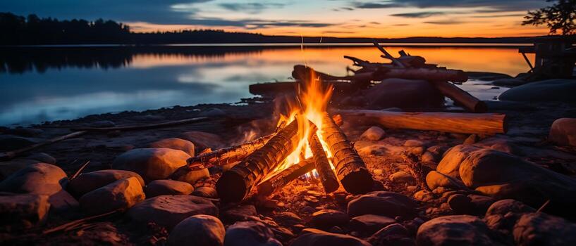 Experience a glowing campfire by the lake, with a stunning sunset and the warmth of open flames, fire, and logs. Enjoy beach camping at night amidst the serene lake landscape. photo
