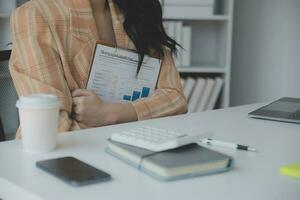 Asian Business woman using calculator and laptop for doing math finance on an office desk, tax, report, accounting, statistics, and analytical research concept photo