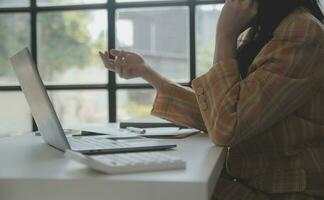 Asian Business woman using calculator and laptop for doing math finance on an office desk, tax, report, accounting, statistics, and analytical research concept photo