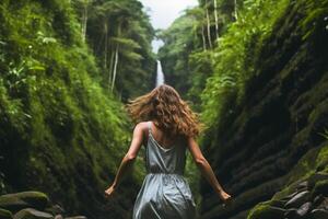 Photo of the back of a woman in summer clothes running toward tropical forests and waterfalls. AI generative