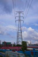 High voltage electricity pylon with cityscape and blue sky background. photo