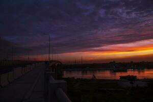 Sunset over the river in the city. The bridge crosses the river photo