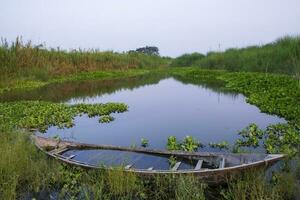 estanque azul agua y de madera barco con reflejándose apuntalar verde césped paisaje ver foto